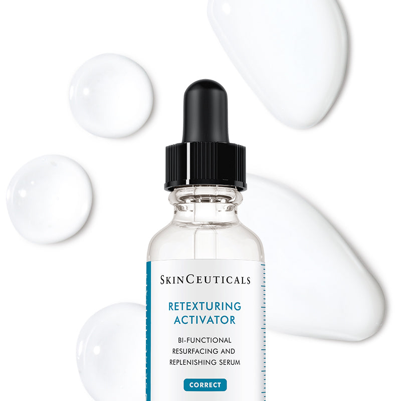 SkinCeuticals Retexturing Activator serum in a clear glass dropper bottle with a black cap, centered on a white background with decorative white cream blobs.