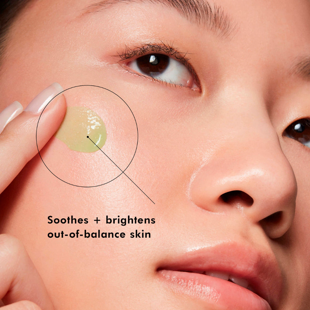Close-up of a person applying a green gel patch of SkinCeuticals Phyto A+ Brightening Treatment Moisturizer to their skin with text indicating it soothes and brightens skin.