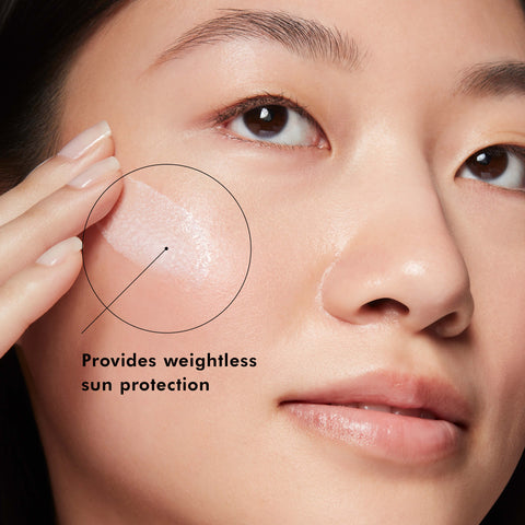Close-up of a person applying SkinCeuticals Sheer Physical SPF 50 Sunscreen to their face with text indicating weightless sun protection.