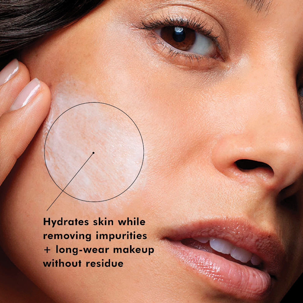 Close-up of a woman's face with a circular highlighted area on her cheek showing a light, hydrated complexion, accompanied by text that reads 'Hydrates skin while removing impurities + long-wear makeup without residue'.