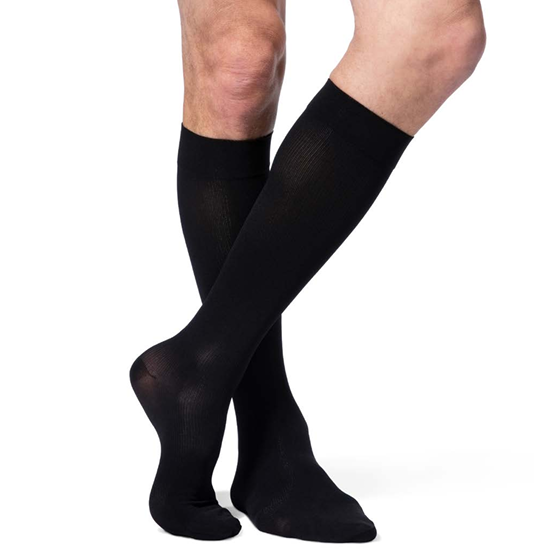 A pair of black knee-high compression socks worn on a person's legs, shown against a plain white background.