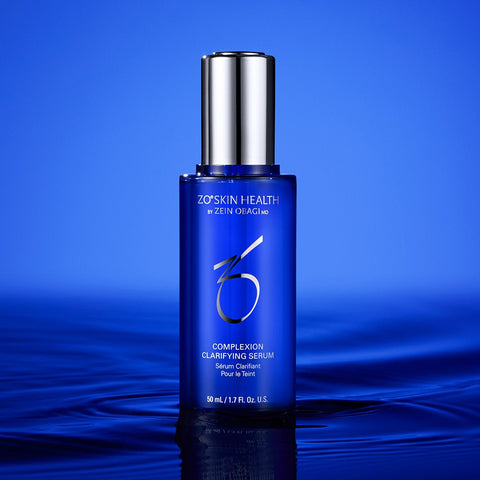 Zo Skin Health Complexion Clarifying Serum in a blue bottle with a silver cap, standing on a reflective dark blue surface against a blue gradient background.